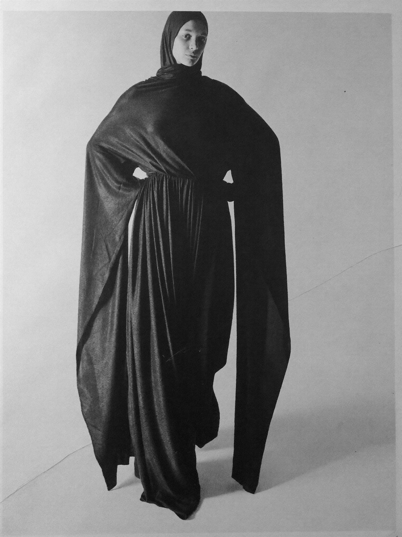 Monochrome editorial figure, draped black tailoring.