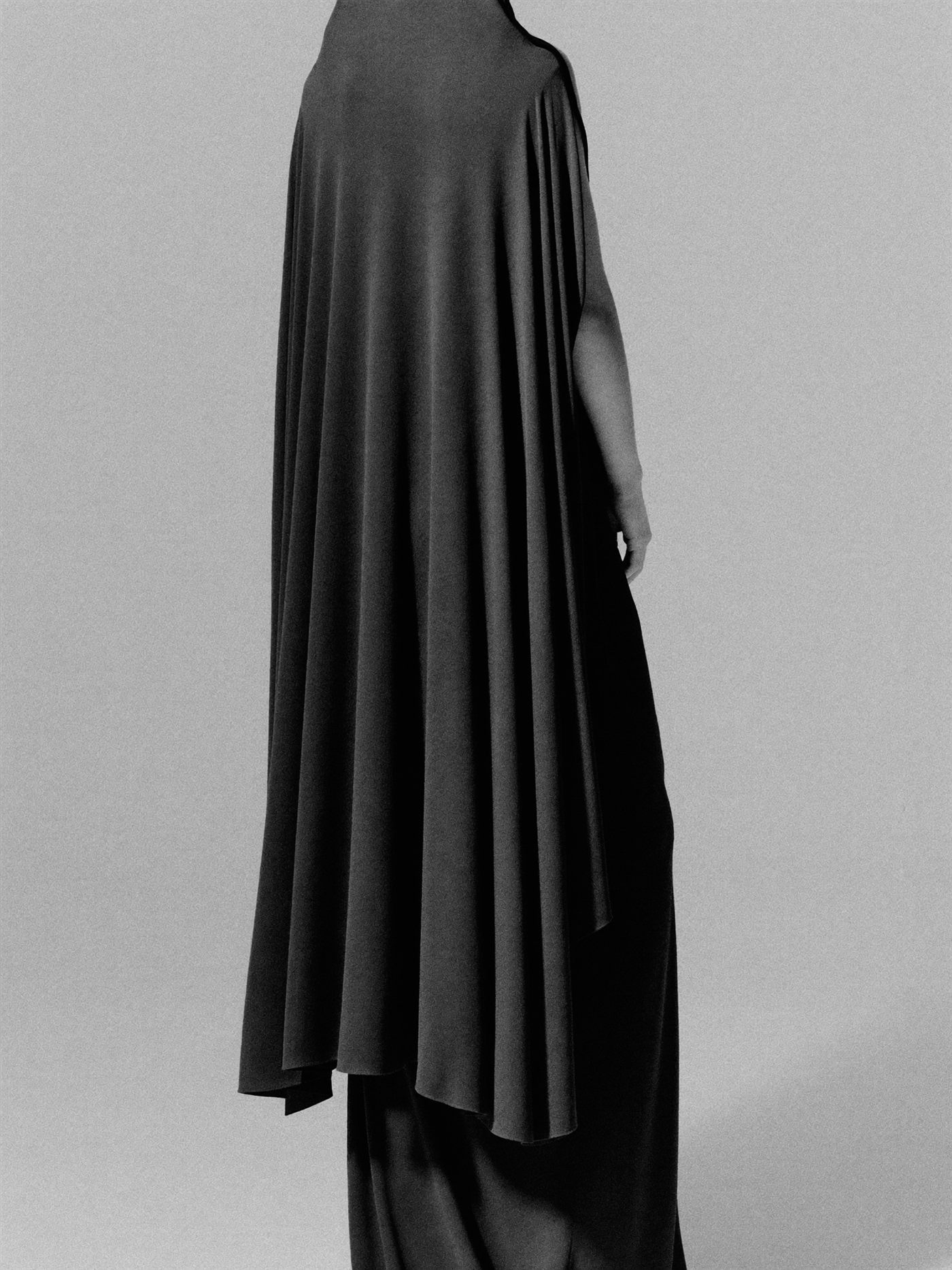 Full-length monochrome silhouette in flowing black garment.